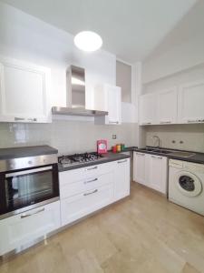 a kitchen with white cabinets and a stove top oven at White Sea - Luminoso Appartamento a 200mt dal mare in Spadafora