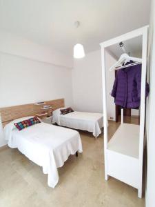 a white room with two beds and a mirror at White Sea - Luminoso Appartamento a 200mt dal mare in Spadafora