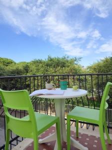 einen Tisch und zwei grüne Stühle auf einer Terrasse in der Unterkunft White Sea - Luminoso Appartamento a 200mt dal mare in Spadafora