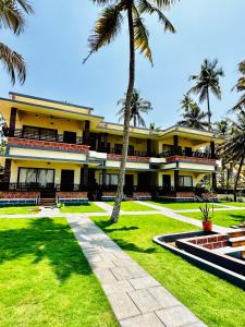 a yellow building with palm trees in front of it at Maadathil Beach Resort in Varkala