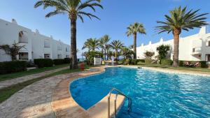 uma piscina com palmeiras e edifícios em Arenes By El Conserje em Denia