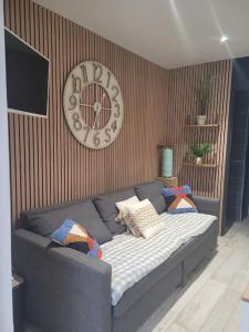 un divano in un soggiorno con un orologio sul muro di Studio Cosy " La Tarente Dorée " a Fréjus Altre 10 foto