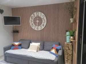 un divano blu in soggiorno con un orologio sul muro di Studio Cosy " La Tarente Dorée " a Fréjus