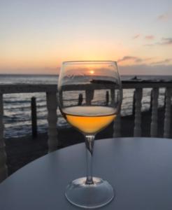 una copa de vino sentada en una mesa con el océano en VV YELYMAR. PLAYA DE ALOJERA en Alojera