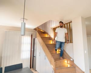 Ein Mann, der in einem Haus eine Holztreppe hinuntergeht in der Unterkunft Happinest Private Suite with Jacuzzi in Kalymnos