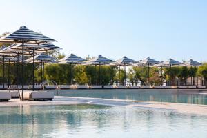 een zwembad met parasols, stoelen en water bij Doryssa Seaside Resort in Pythagoreio