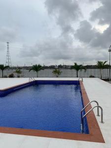 a swimming pool with blue water in front of a fence at WATERFRONT 3BR APT W/FREE PARKIN WiFi NETFLIX POOL in Lagos