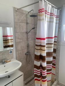 a bathroom with a shower curtain and a sink at La Bandolaise à Perdika in Perdhika