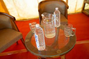 una mesa de cristal con vasos y botellas de agua. en Bluebird Desert Resort en Jaisalmer