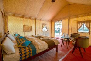 a bedroom with a large bed and a table at Bluebird Desert Resort in Jaisalmer