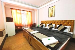 een grote slaapkamer met een groot bed met een houten hoofdeinde bij Retreat Hotel Samden, Darjeeling in Darjeeling