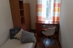 um quarto com uma secretária, uma cama e uma cadeira em 8 min to Castel & Main Square na Cracóvia