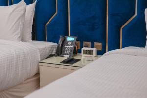 a hotel room with a phone on a table between two beds at La Cordia Hotel Apartment in Al Madinah +46 photos