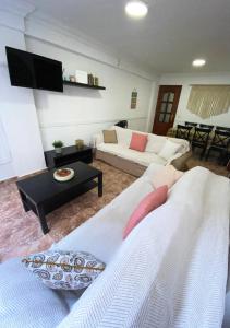 uma sala de estar com dois sofás brancos e uma televisão em Apartamento Deborah em Málaga