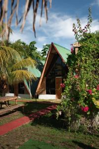 a house with a green roof and a bench and flowers at Glamping Alona in Panglao
