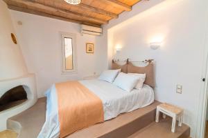 a white bedroom with a bed and a stool at Panormos Art Villas & Suites in Pánormos
