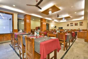 The Posh Hotel في ماكليود غانج: مطعم بالطاولات والكراسي مع طاولة قماش حمراء