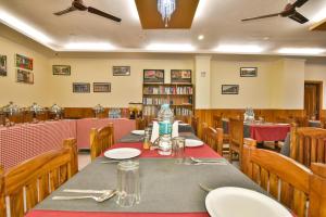 uma sala de jantar com uma mesa longa e cadeiras em The Posh Hotel em McLeod Ganj