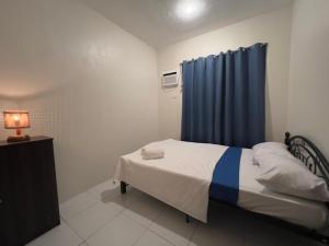 - une chambre avec un lit et un rideau bleu dans l'établissement Casa Via: Cozy 3 Bedroom Home in Bacolod with Parking, à Bacolod