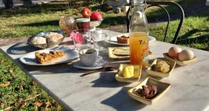 una mesa con platos de comida y una botella de zumo en Chambre d'hôte 1787 : Les Terrasses des Pyrénées en Laloubère