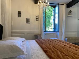1 dormitorio con cama, ventana y lámpara de araña en Chambre d'hôte 1787 : Les Terrasses des Pyrénées en Laloubère