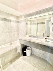 La salle de bains est pourvue d'un lavabo, d'une baignoire et d'un miroir. dans l'établissement Sun Riviera Hotel, à Cannes