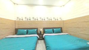 twee bedden in een kamer met blauwe kussens bij Uyên House hotel in Da Lat