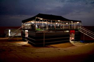 un edificio con luces en la playa por la noche en Rashid Desert Private Camp, en Badīyah