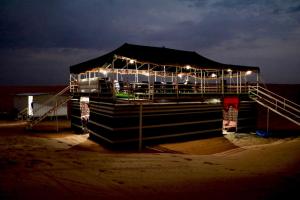 a building with lights on the beach at night at Rashid Desert Private Camp in Bidiyah