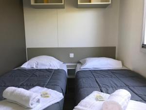 - 2 lits dans une chambre avec des serviettes dans l'établissement CAMP'HOTEL LE THAO LA ROCHELLE-ILE DE RE, à LʼHoumeau