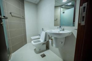 een badkamer met een toilet, een wastafel en een spiegel bij Niamey Mall & Residence in Niamey