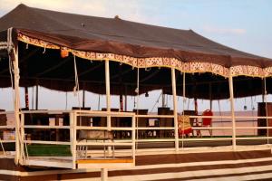 - un kiosque avec un toit noir sur la plage dans l'établissement Rashid Desert Private Camp, à Badīyah