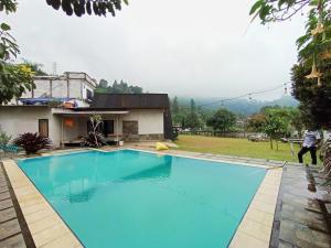 a large blue swimming pool in front of a house at Villa Cisarua Kerucut in Brujul