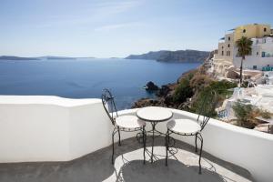 a table and chairs on a balcony overlooking the ocean at Ducato Di Oia in Oia