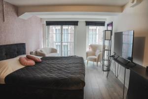 a bedroom with a bed and a living room with windows at The Residence Deventer in Deventer