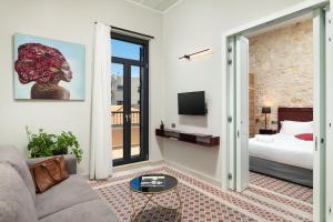 een woonkamer met een bank, een bed en een tv bij The Alma City Hotel in Chania