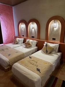 two beds in a room with three windows at Dar Hassan Merzouga in Merzouga