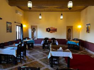 uma sala de jantar com mesas, cadeiras e luzes em Dar Hassan Merzouga em Merzouga