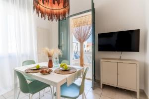a dining room with a white table with chairs and a tv at Casa Olimpo vicino alle spiagge di sabbia in Specchiolla 