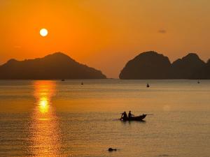 two people in a boat in the water at sunset at Phoenix Flower Hotel in Cat Ba