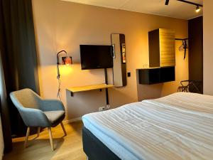 1 dormitorio con 1 cama, 1 silla y TV en Hotell Nyboholm, en Ulricehamn