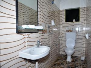 ein Badezimmer mit einem Waschbecken, einem WC und einem Spiegel in der Unterkunft Wembley Villa Diani Beach in Diani Beach