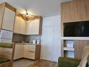 a kitchen with white cabinets and a flat screen tv at Apartman Meggy in Belgrade +6 photos