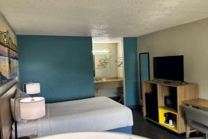 ein Hotelzimmer mit einem Bett und einem Flachbild-TV in der Unterkunft Days Inn by Wyndham Columbia NE Fort Jackson in Columbia