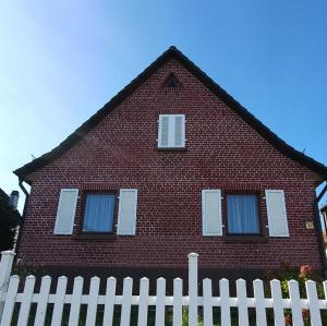 a red brick house with a white fence at Ferienhaus Sommer mit Klimaanlage in Neckarsulm