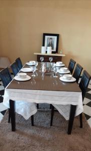 a dining room table with plates and wine glasses on it at Étage RDC villa vu sur mer avec jardin in El Jadida
