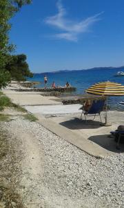 einen Strand mit einem Tisch, einem Stuhl und einem Sonnenschirm in der Unterkunft Apartments Pero in Kožino