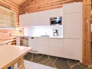 La cuisine est équipée de placards blancs et d'un four micro-ondes. dans l'établissement Holiday Home Karpalo by Interhome, à Ylläsjärvi