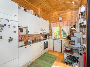 Holiday Home Metsä-iivari by Interhome في Piispala: مطبخ بدولاب بيضاء وسقف خشبي