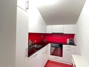 ロイカーバートにあるApartment Ringstrasse - Utoring-49 by Interhomeの赤い床の赤いキッチン(白いキャビネット付)